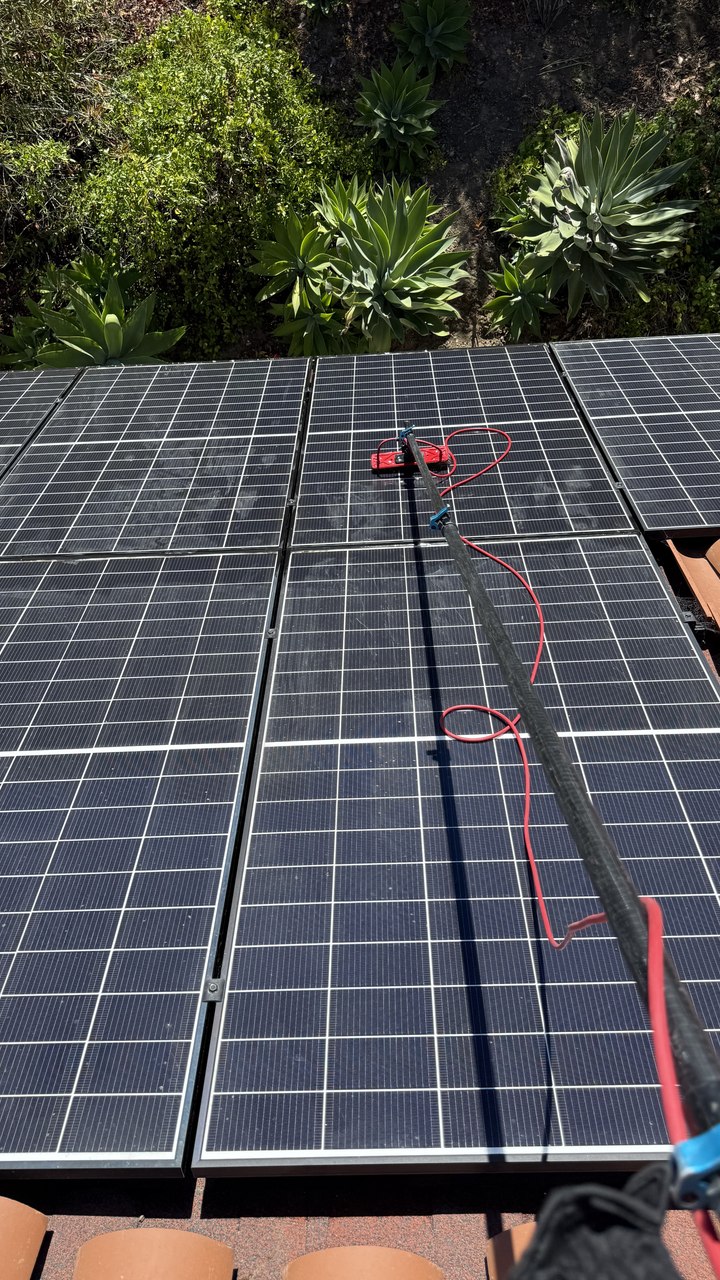 Technician cleaning rooftop solar panels to restore output in Ventura County