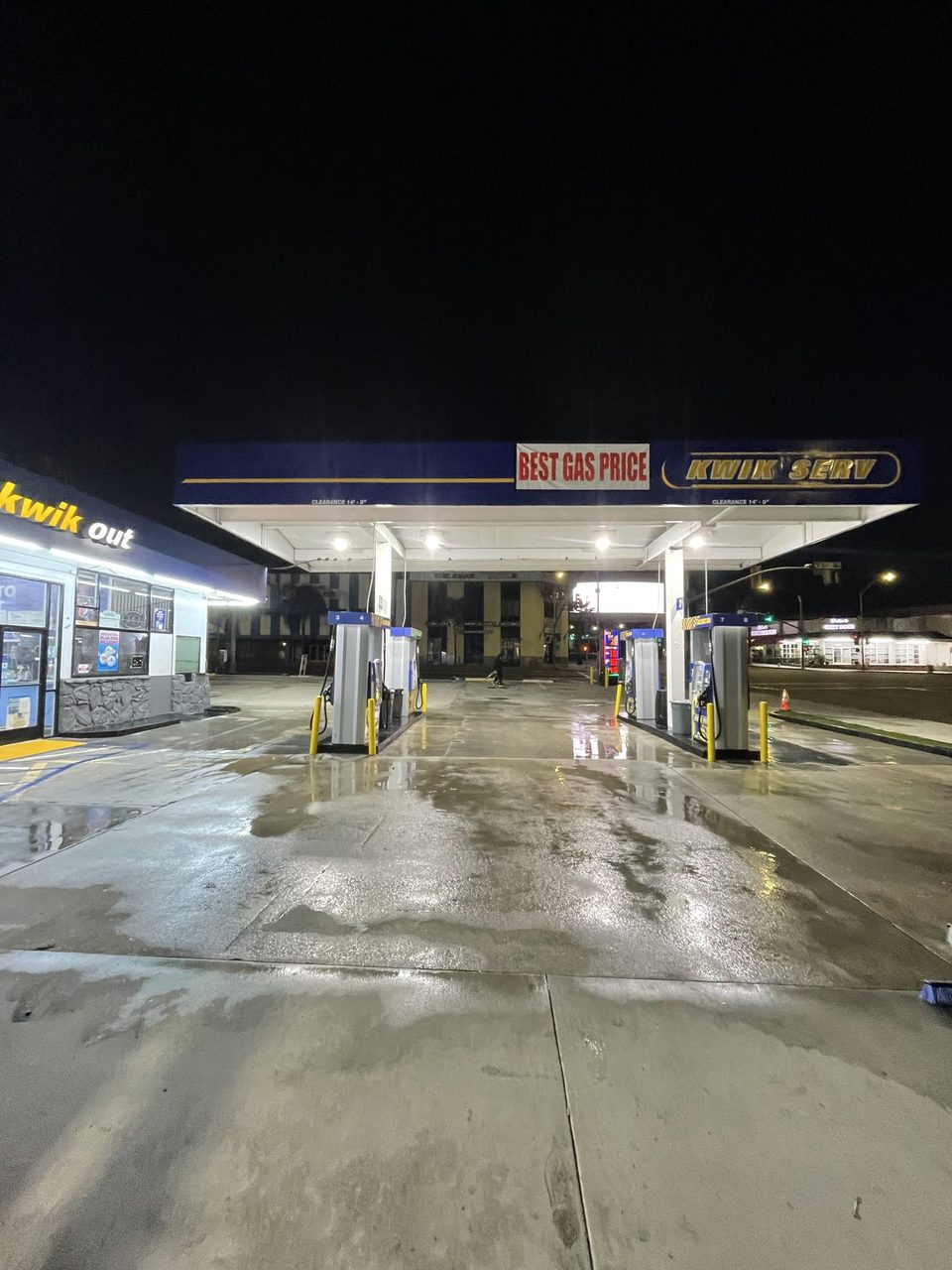 Gas station forecourt after pressure washing, clean wet concrete at night