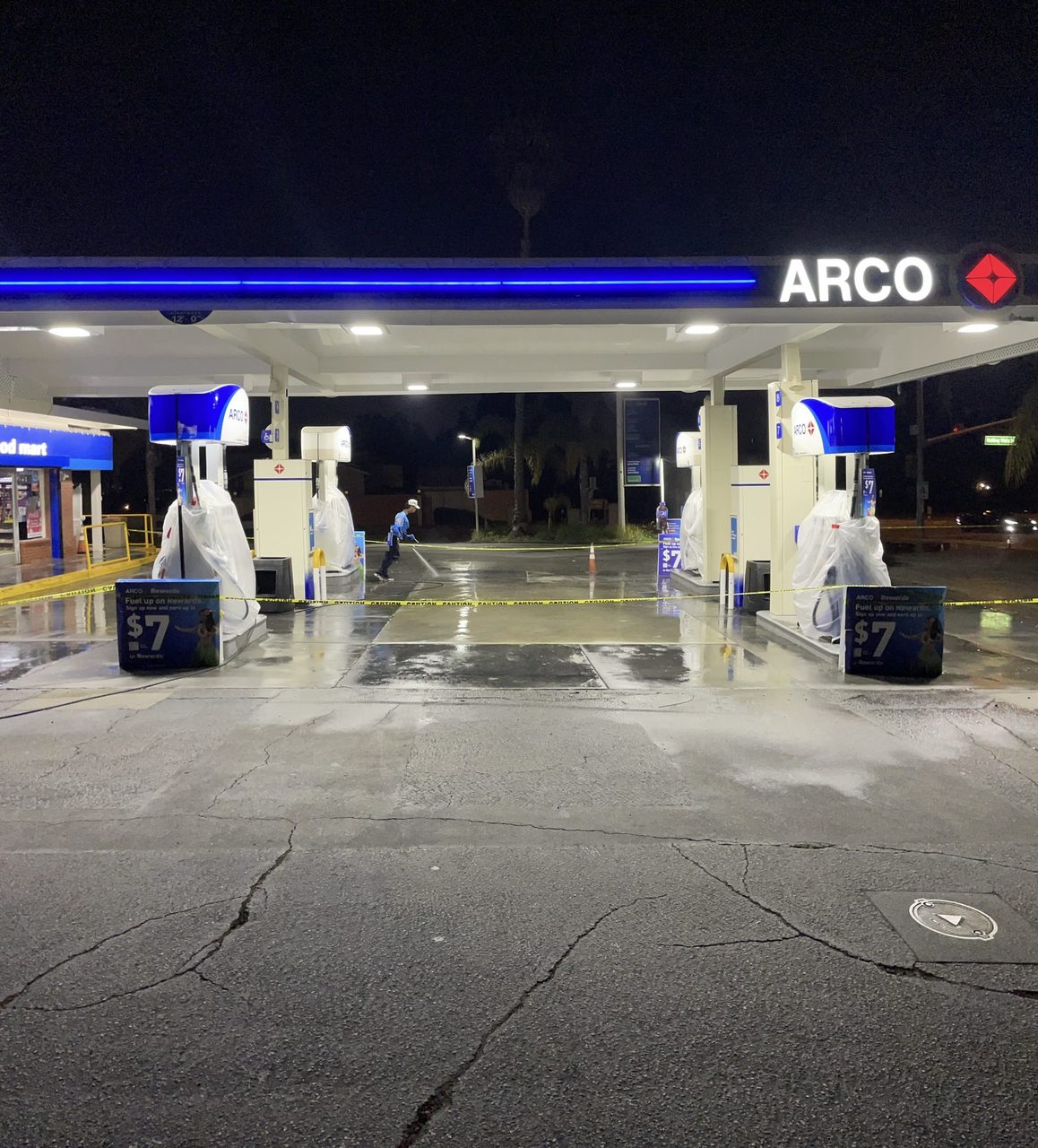 Gas station forecourt before cleaning, stained concrete under the lights