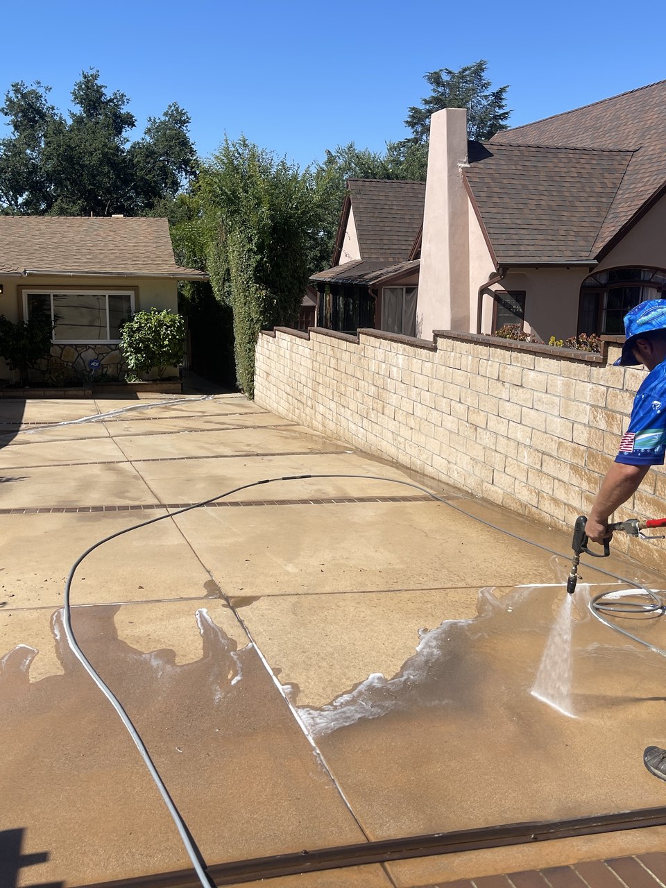 WashPro technician pressure washing a concrete driveway next to the branded van in Los Angeles
